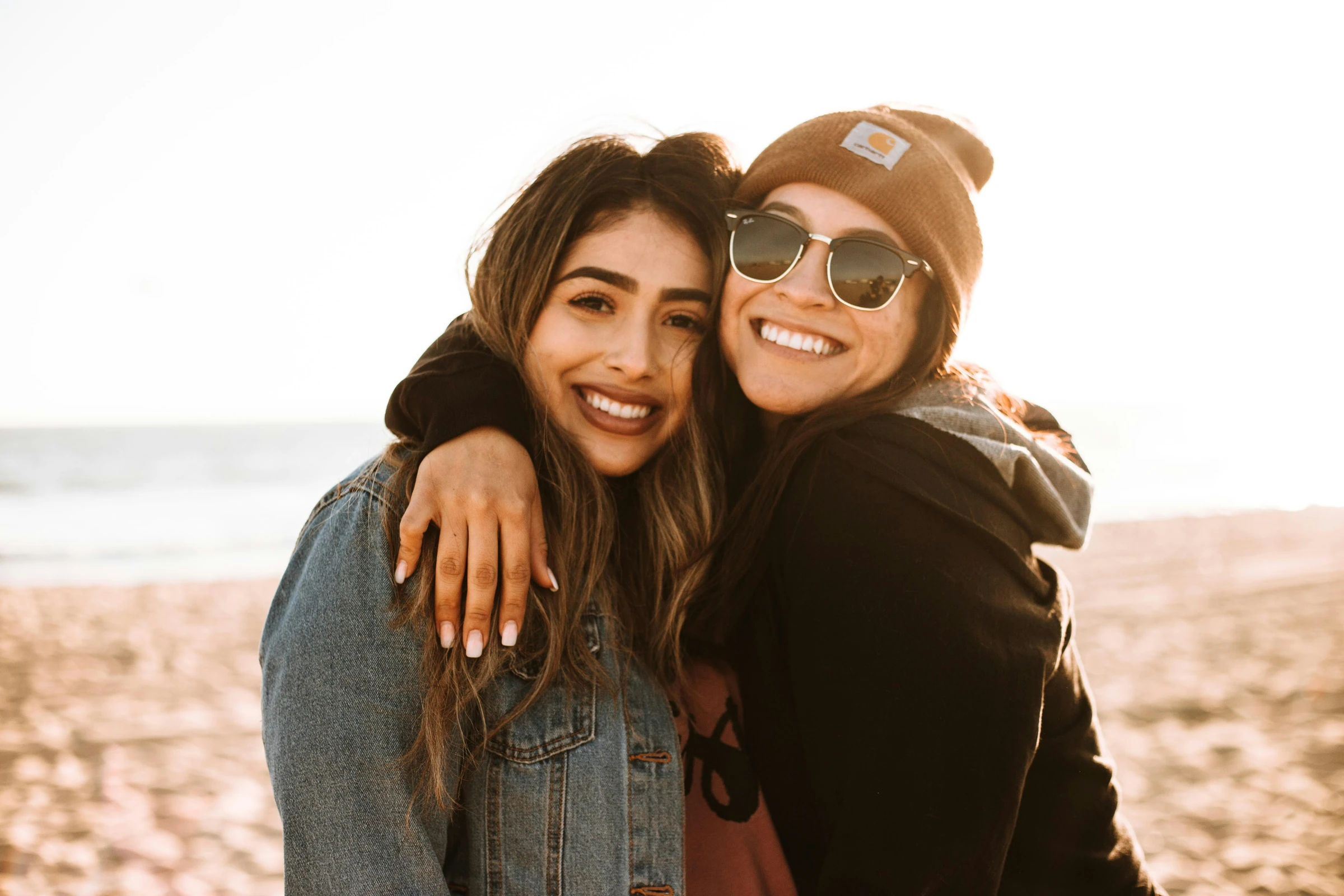 Two friends embracing on the beach, the spirit behind E Ho Mai's invite-a-friend cohorts